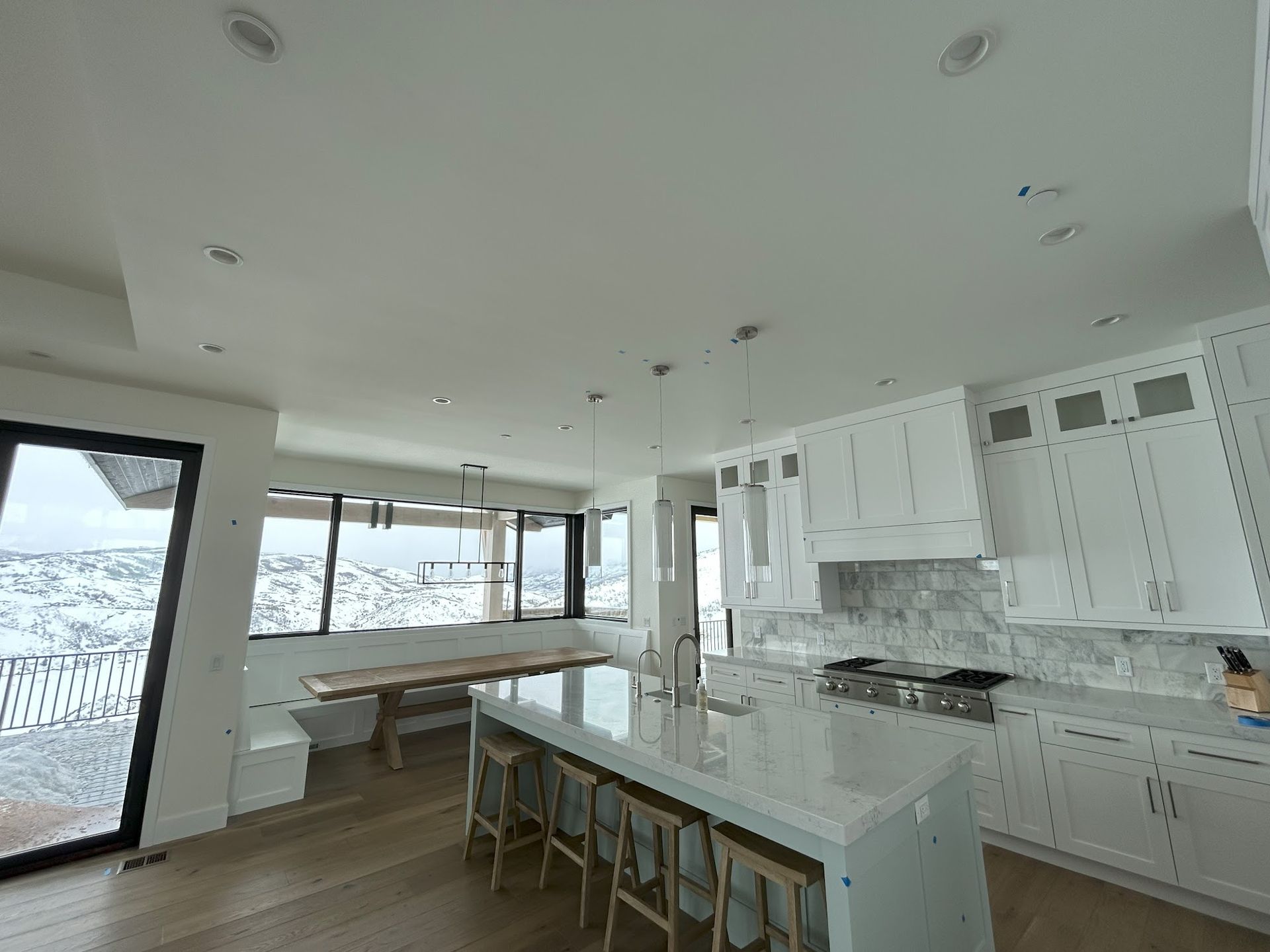 A kitchen with white cabinets and a large island with stools.