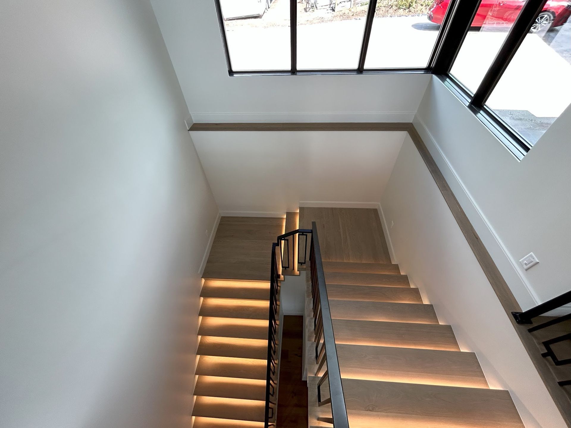 A staircase with lights on the steps and a window in the background.
