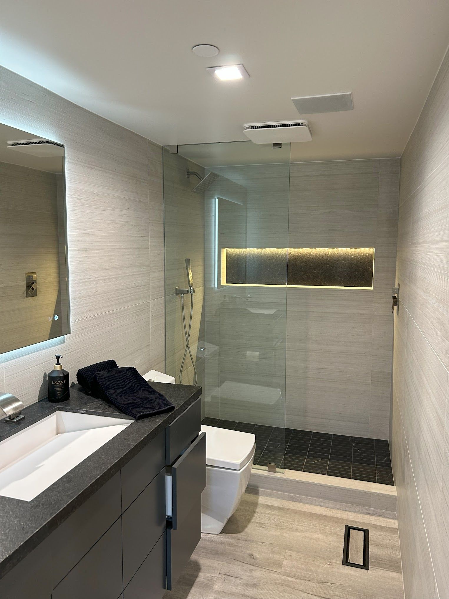 A bathroom with a sink , toilet , shower and mirror.