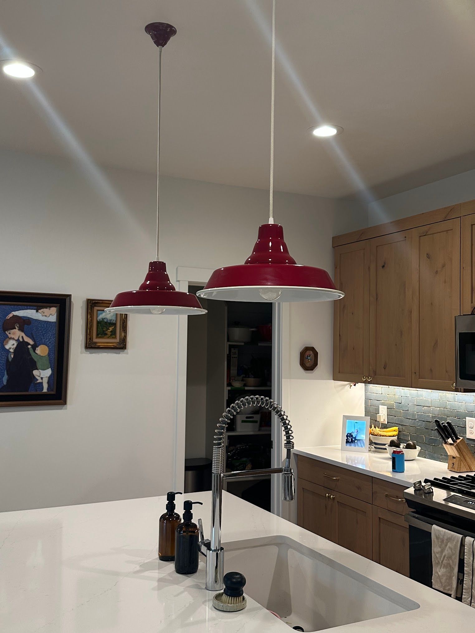 A kitchen with a sink and two red lights hanging from the ceiling