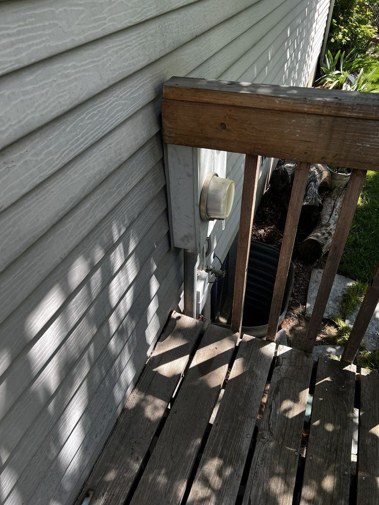 A wooden deck next to a house with a wooden railing.