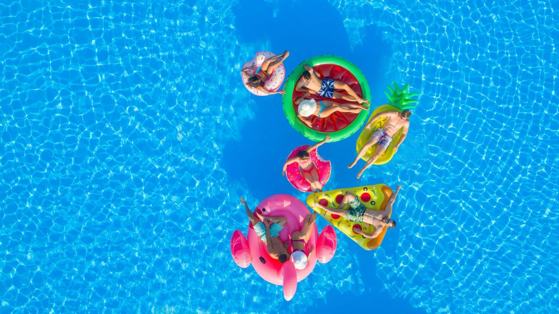 A group of people are floating on rafts in a swimming pool.