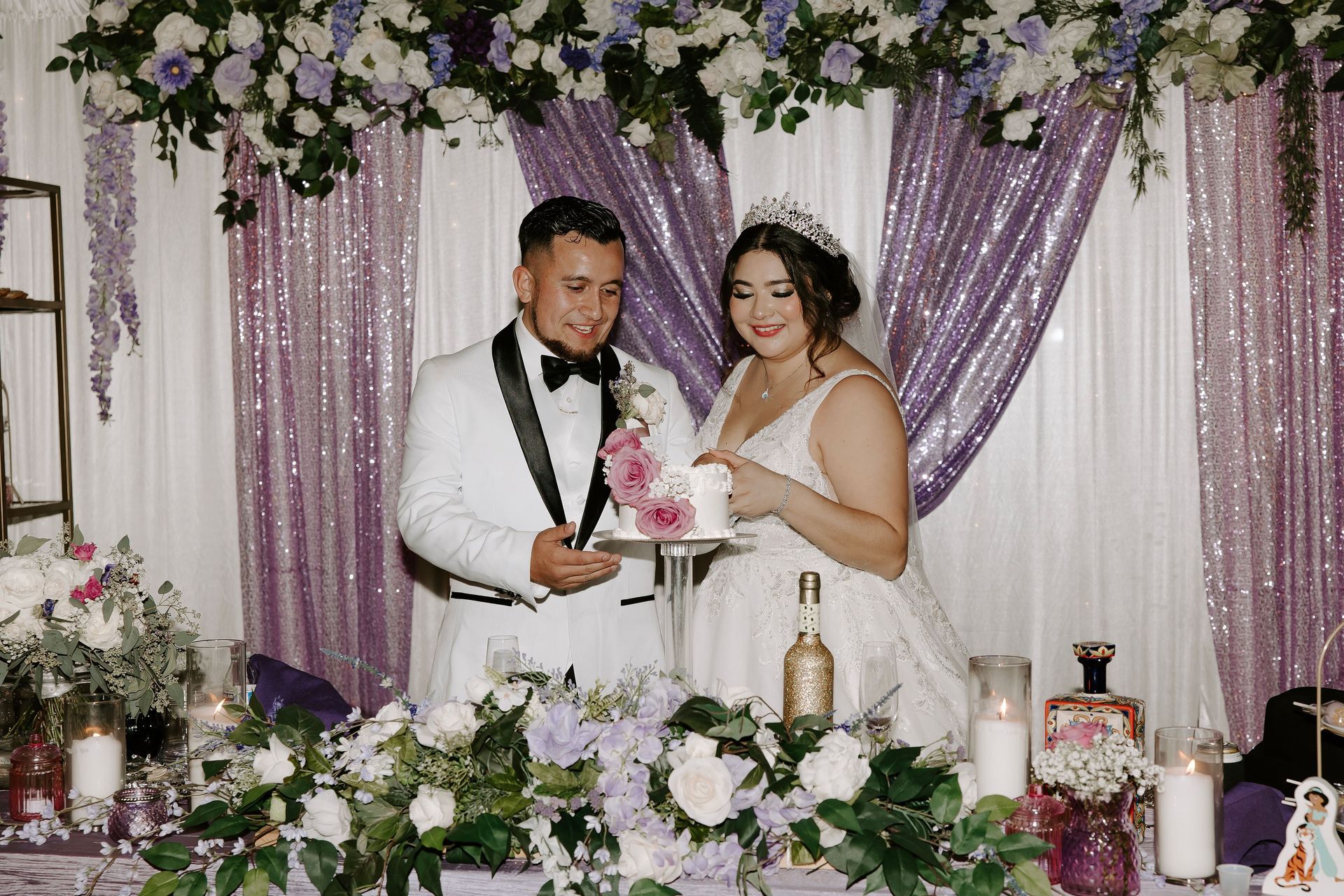 A bride and groom cut their wedding cake in front of a purple backdrop – Pasco, WA - Decoraciones Garcia
