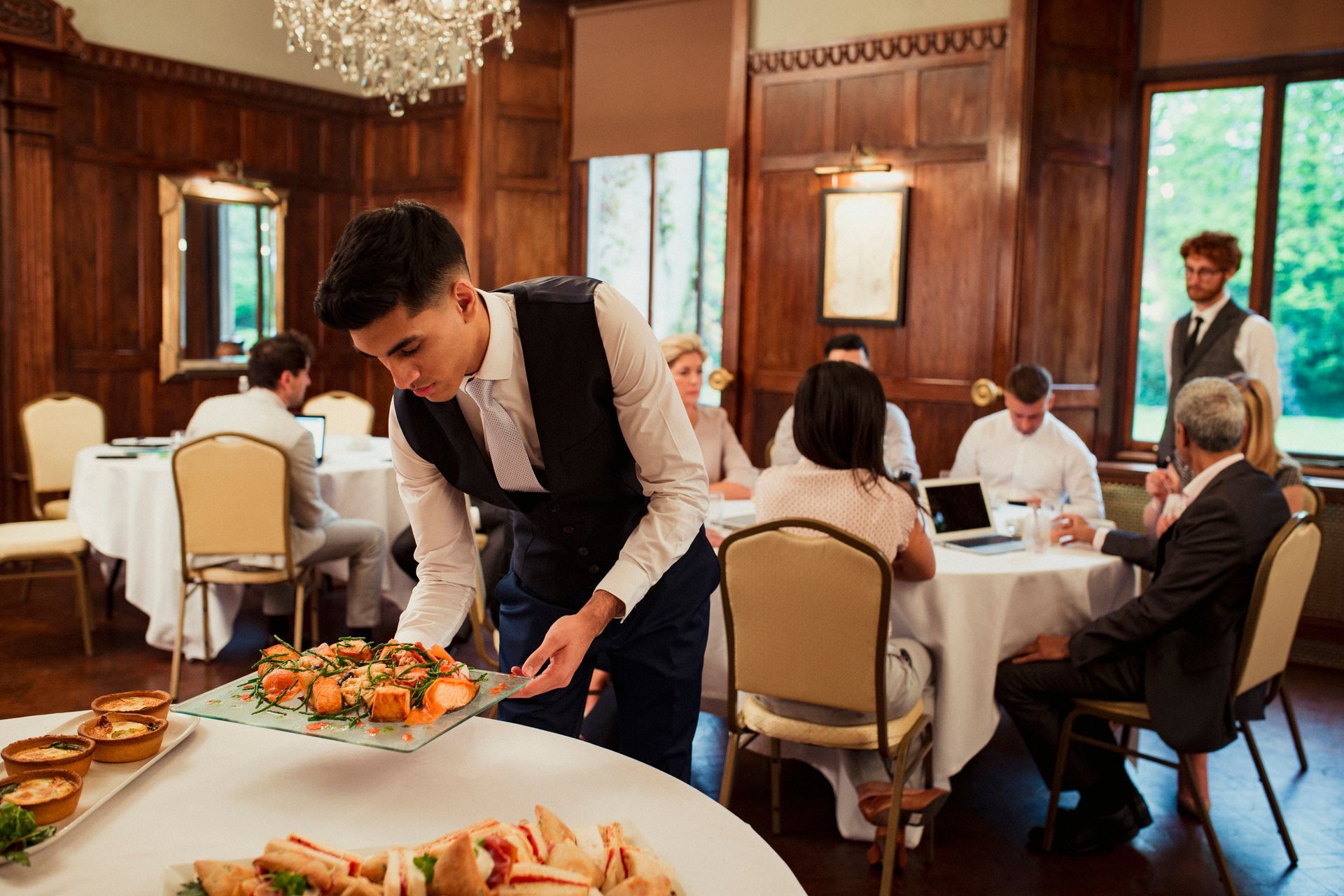 A waiter is serving food to a group of people sitting at tables – Pasco, WA - Decoraciones Garcia