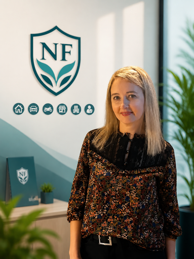 Mujer de pie en una oficina junto a un logotipo del escudo de la NF en la pared.