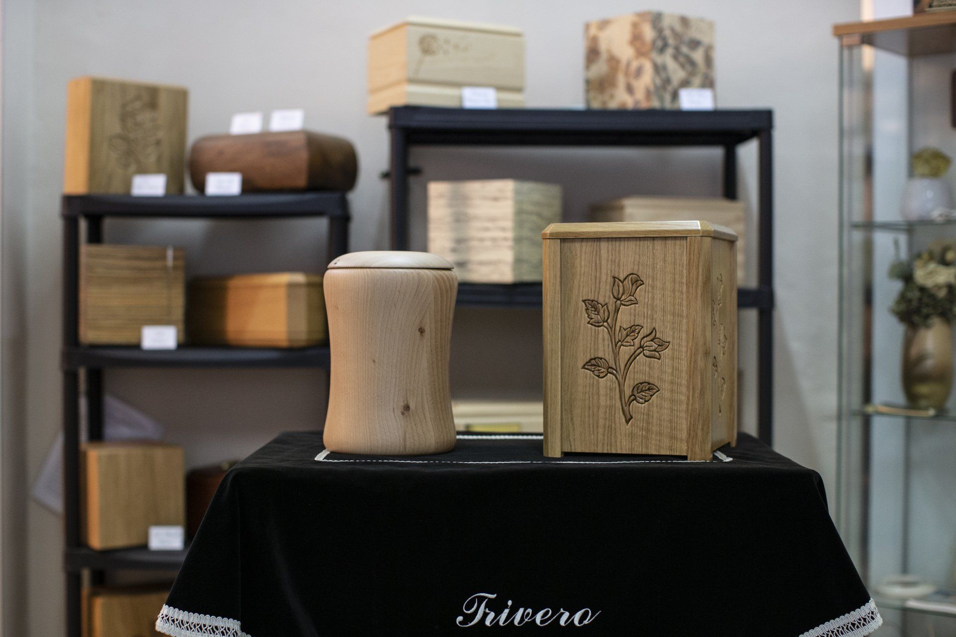 Contenitori in legno esposti su scaffali neri in una stanza illuminata da una luce soffusa.