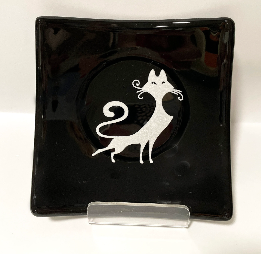 A black plate with a white cat on it