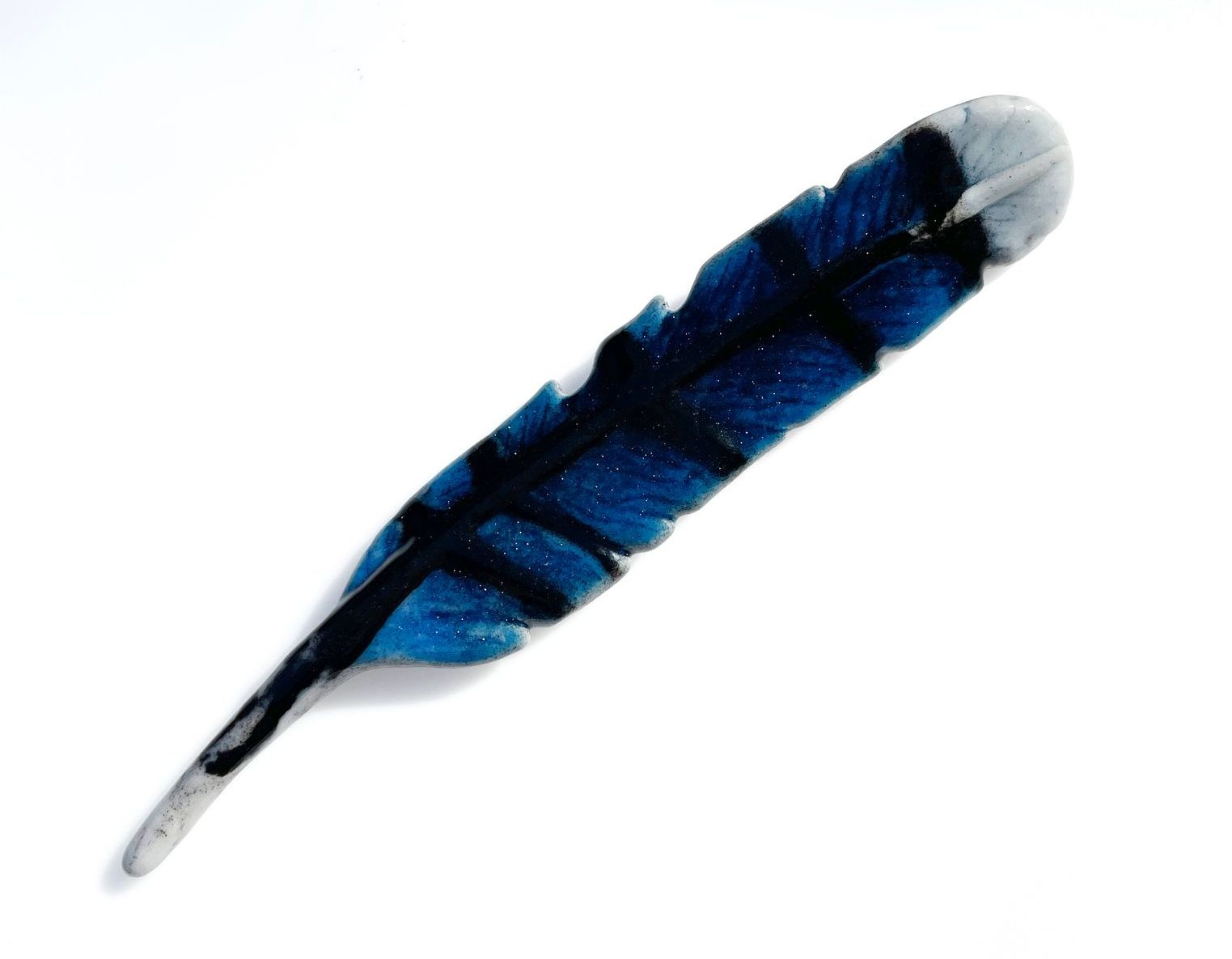 A blue and black feather on a white background