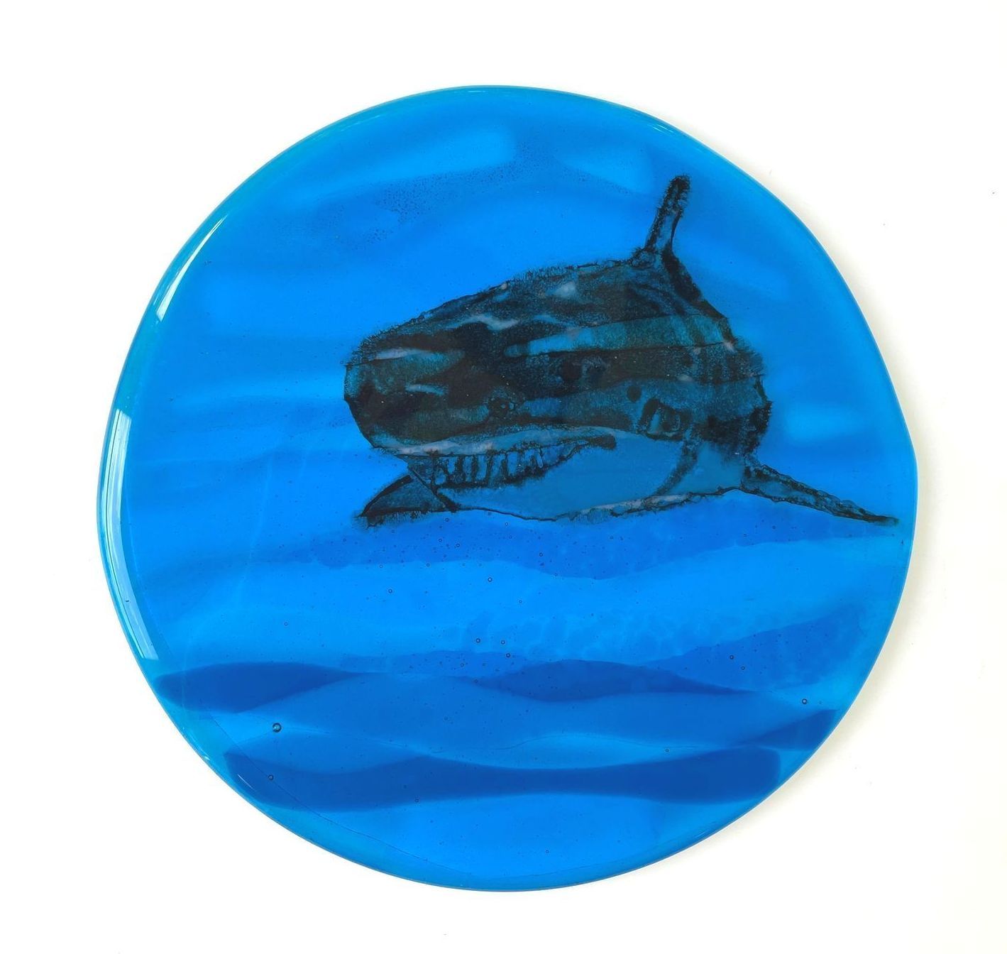 A blue glass circle with a swimming shark.