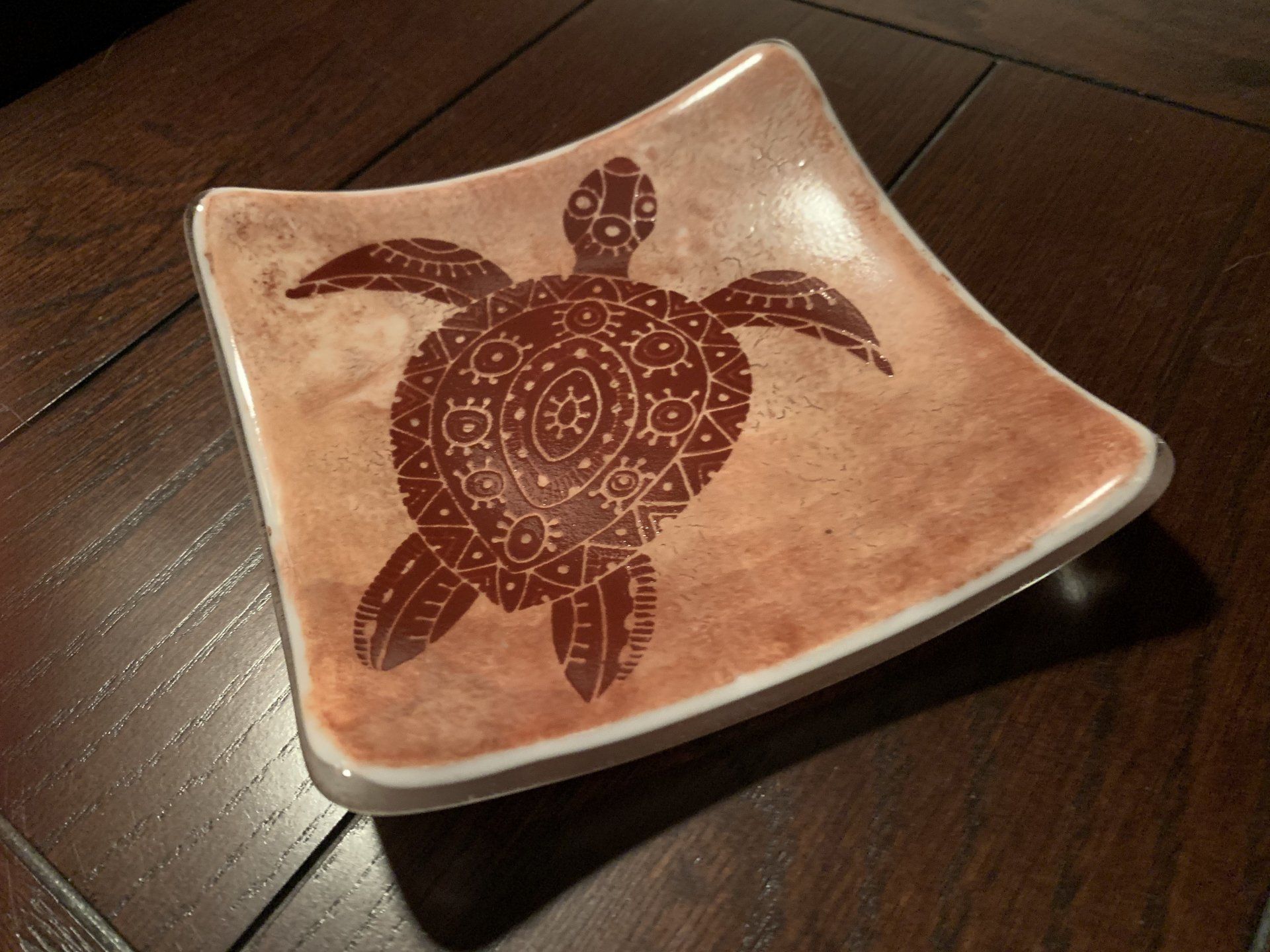 a square plate with a turtle design printed on it in brown