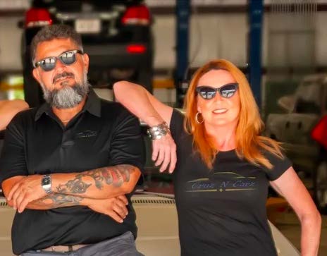 A man and a woman are posing for a picture in a garage.