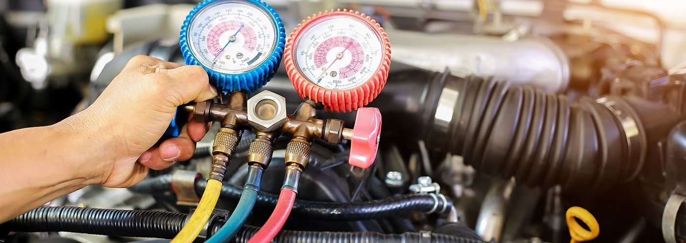 Hand using HVAC gauges on car air conditioning lines during repair