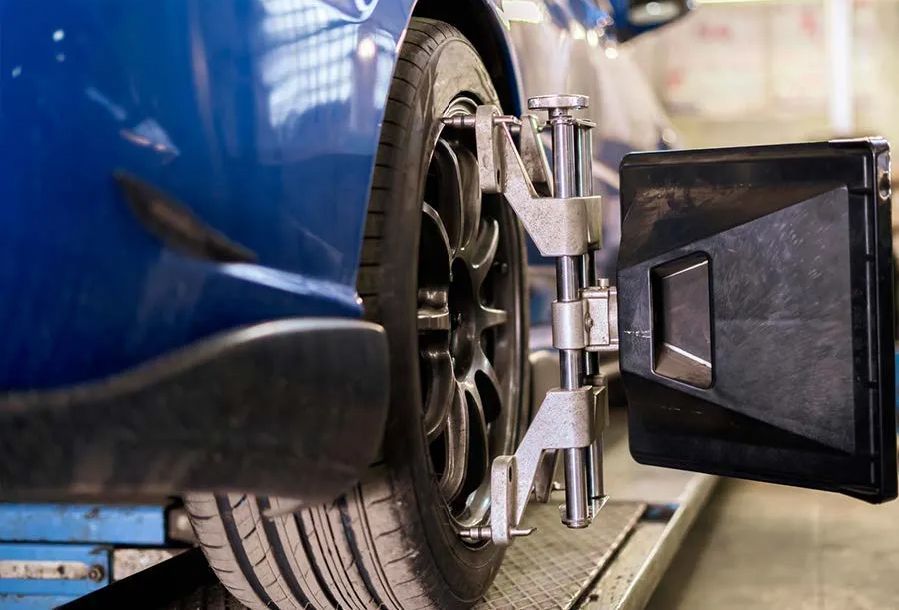 A blue car tire mounted on a machine for wheel alignment.