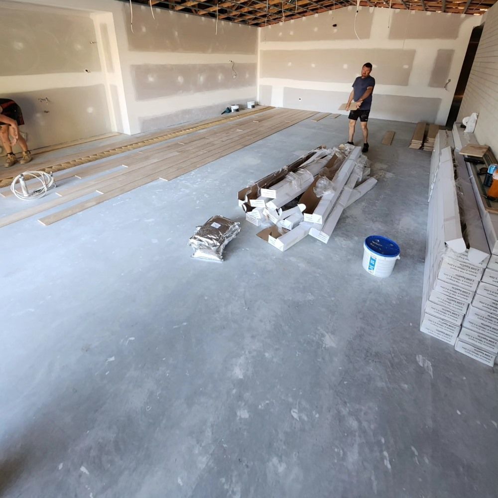 A Man Standing in a Room With a Bucket That Has the Letter B on It — ATM Floors In Mount Louisa, QLD