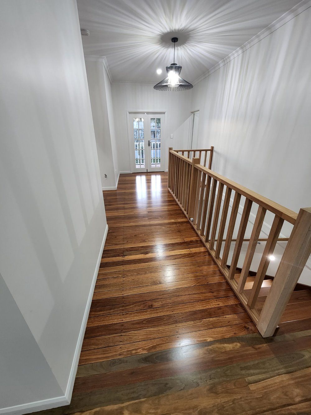 A Hallway With Wooden Floors and Stairs in a House — ATM Floors In Mount Louisa, QLD