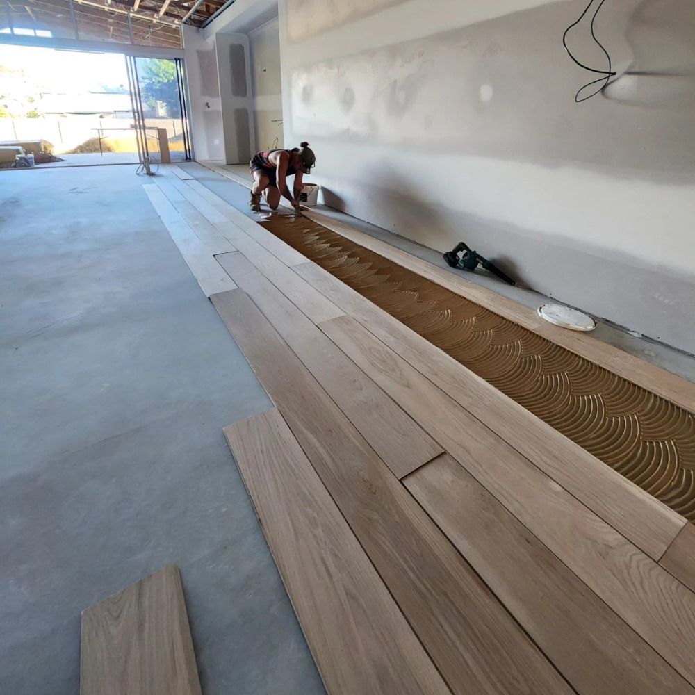 A Person is Laying Wooden Flooring in a Room — ATM Floors In Mount Louisa, QLD
