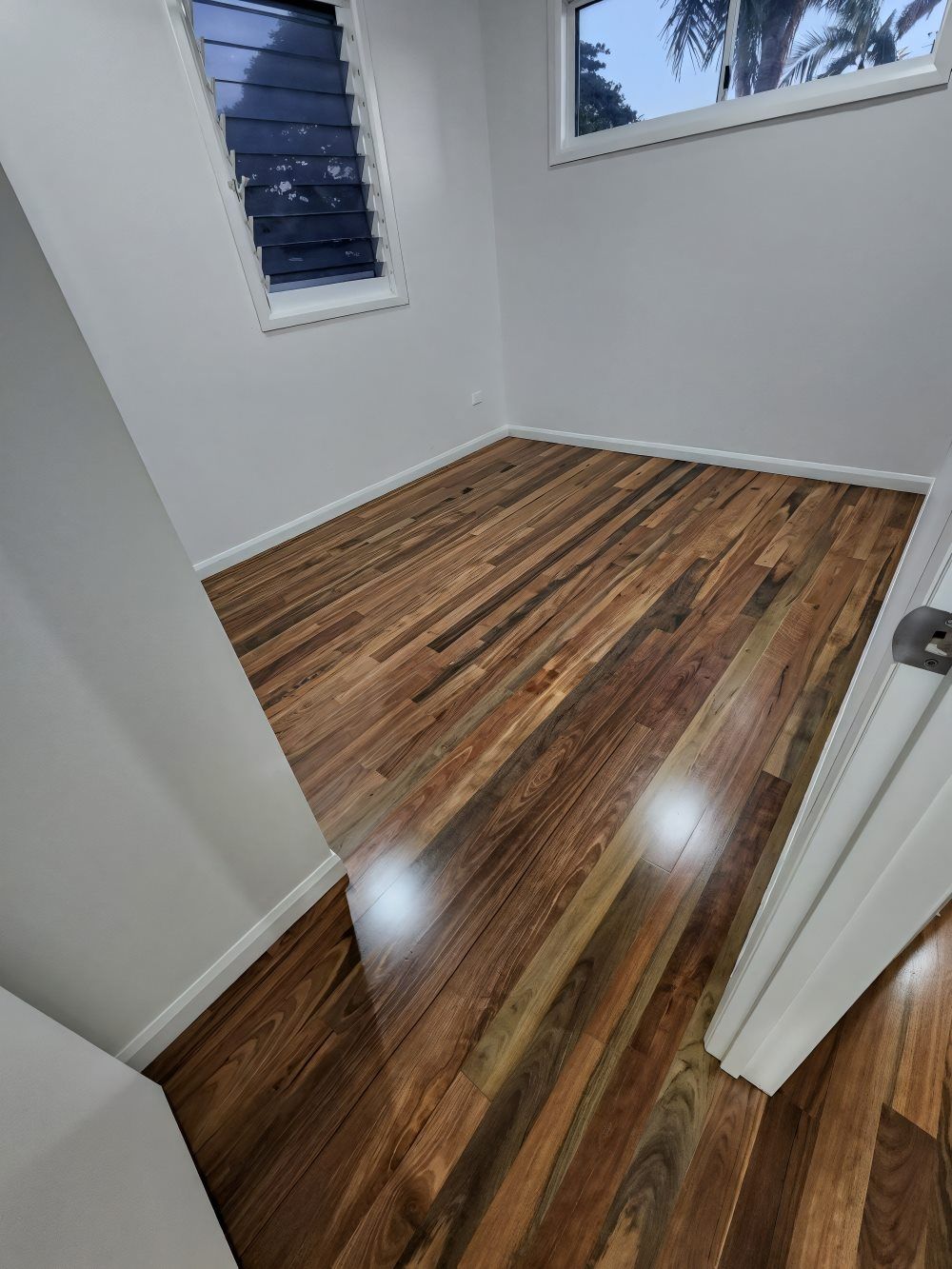 A Living Room With a Wooden Floor and a Brick Wall — ATM Floors In Mount Louisa, QLD