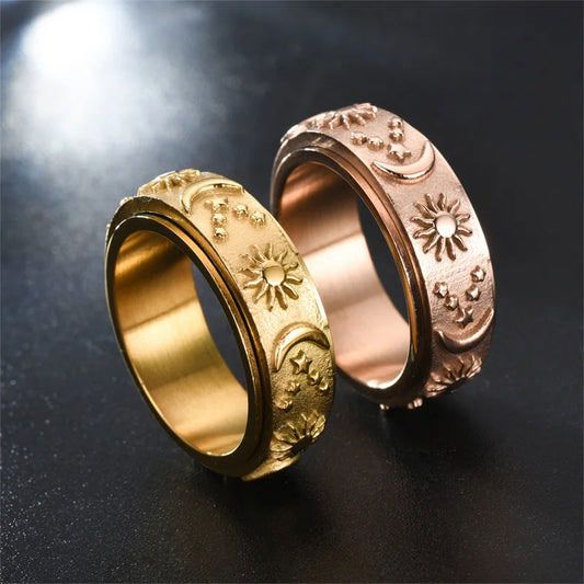 Two celestial-themed spinner rings, one gold and one rose gold, displaying sun, moon, and star engravings.