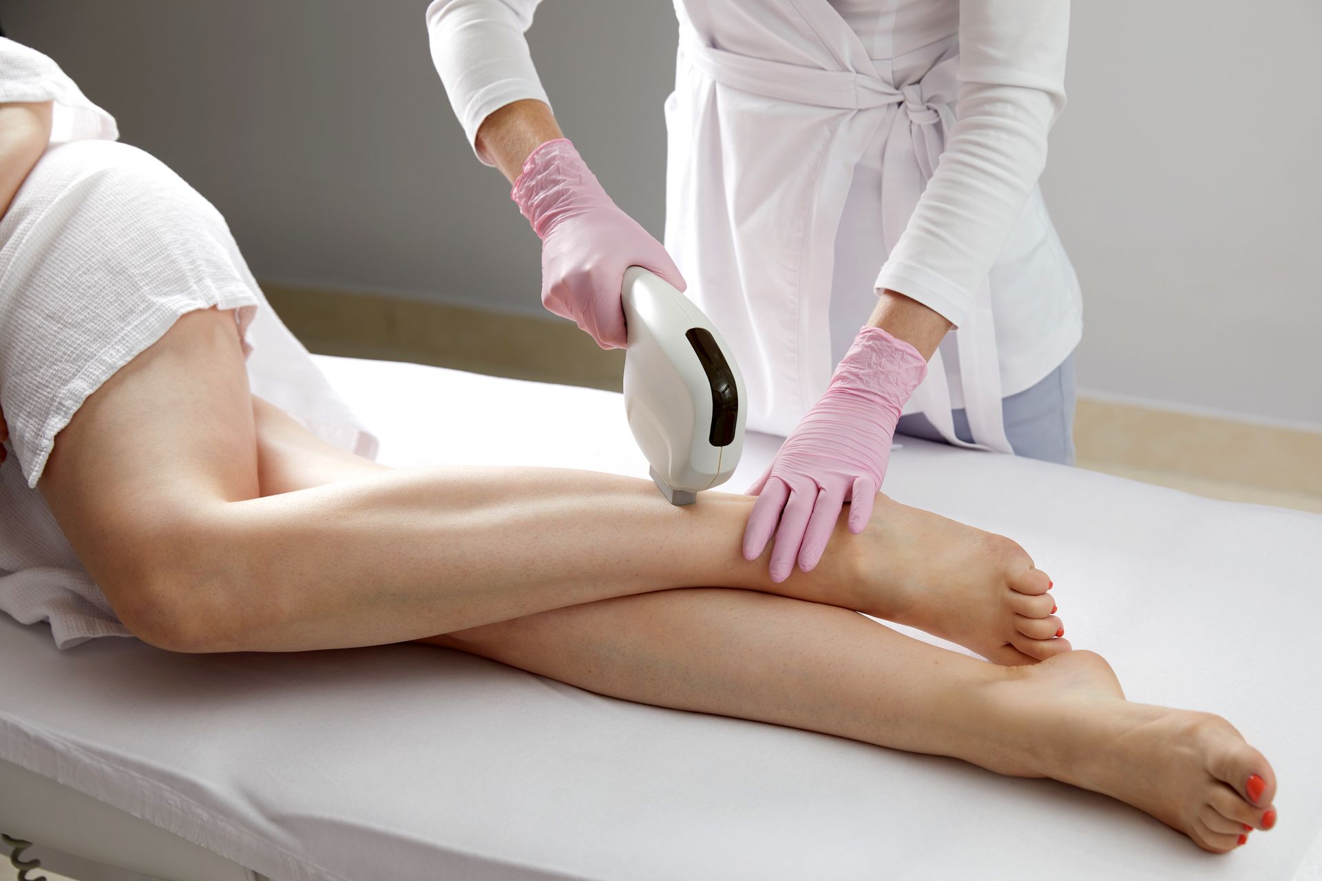 A woman is getting a laser hair removal treatment on her legs.