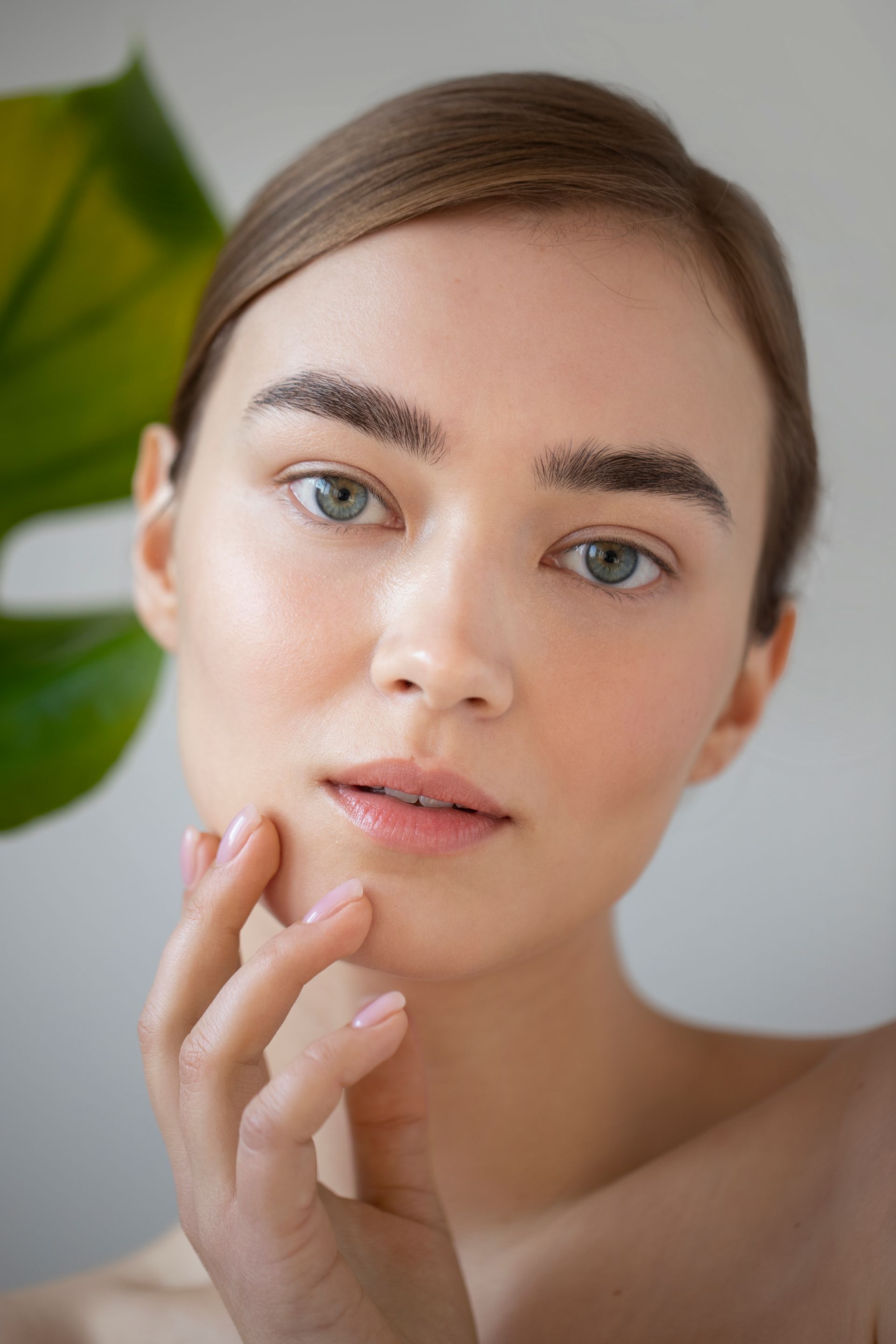 A close up of a woman 's face with a plant in the background.