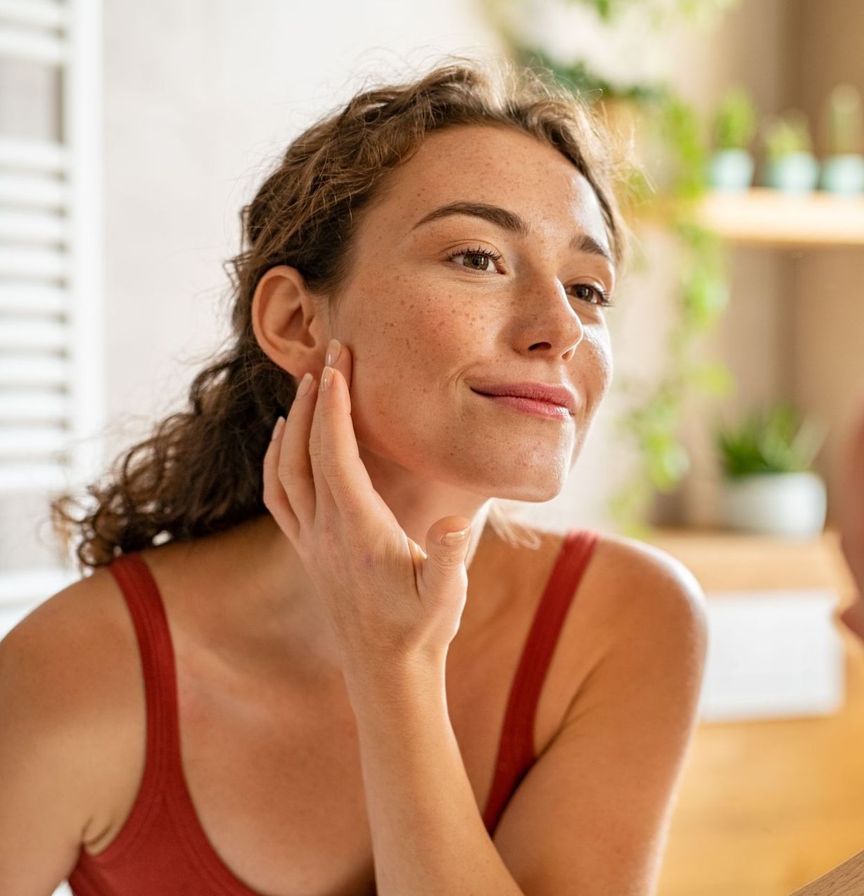 A woman is looking at her face in the mirror.