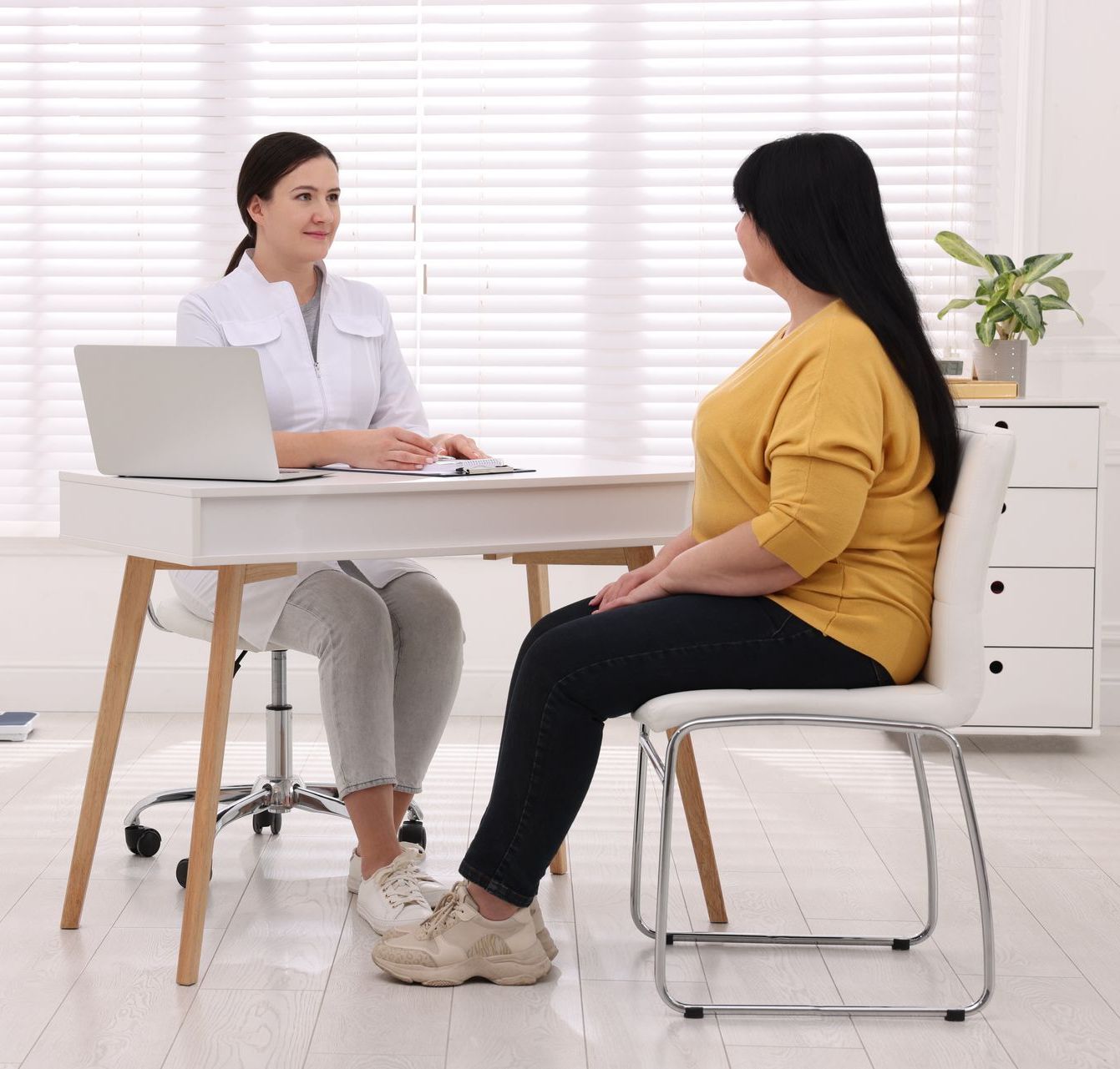 A woman is sitting at a table talking to a doctor.