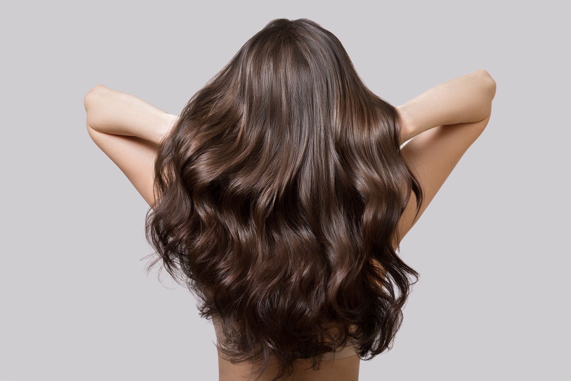 A woman with long brown hair is standing with her arms outstretched.