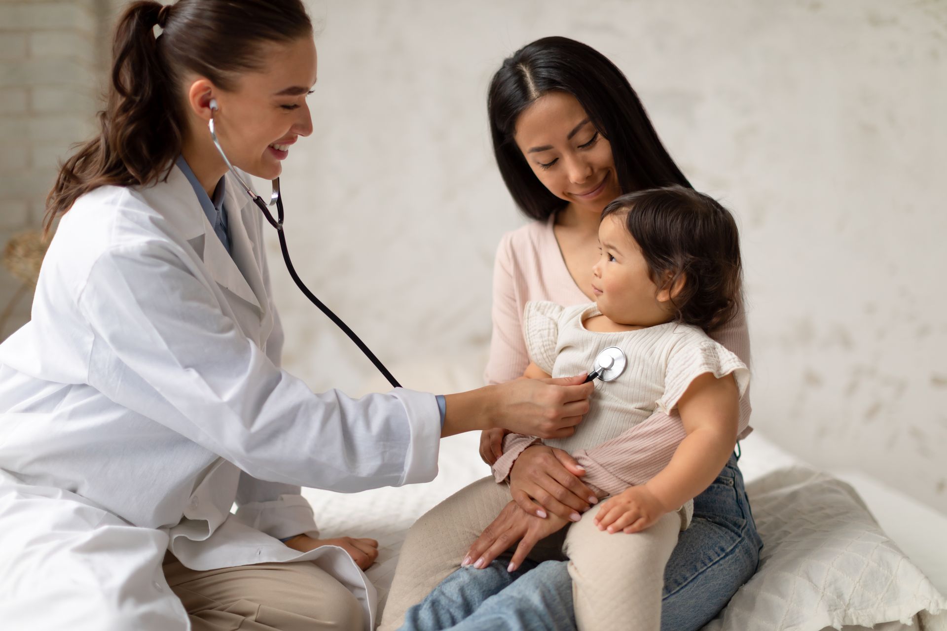 A doctor is listening to a little girl 's heart with a stethoscope.