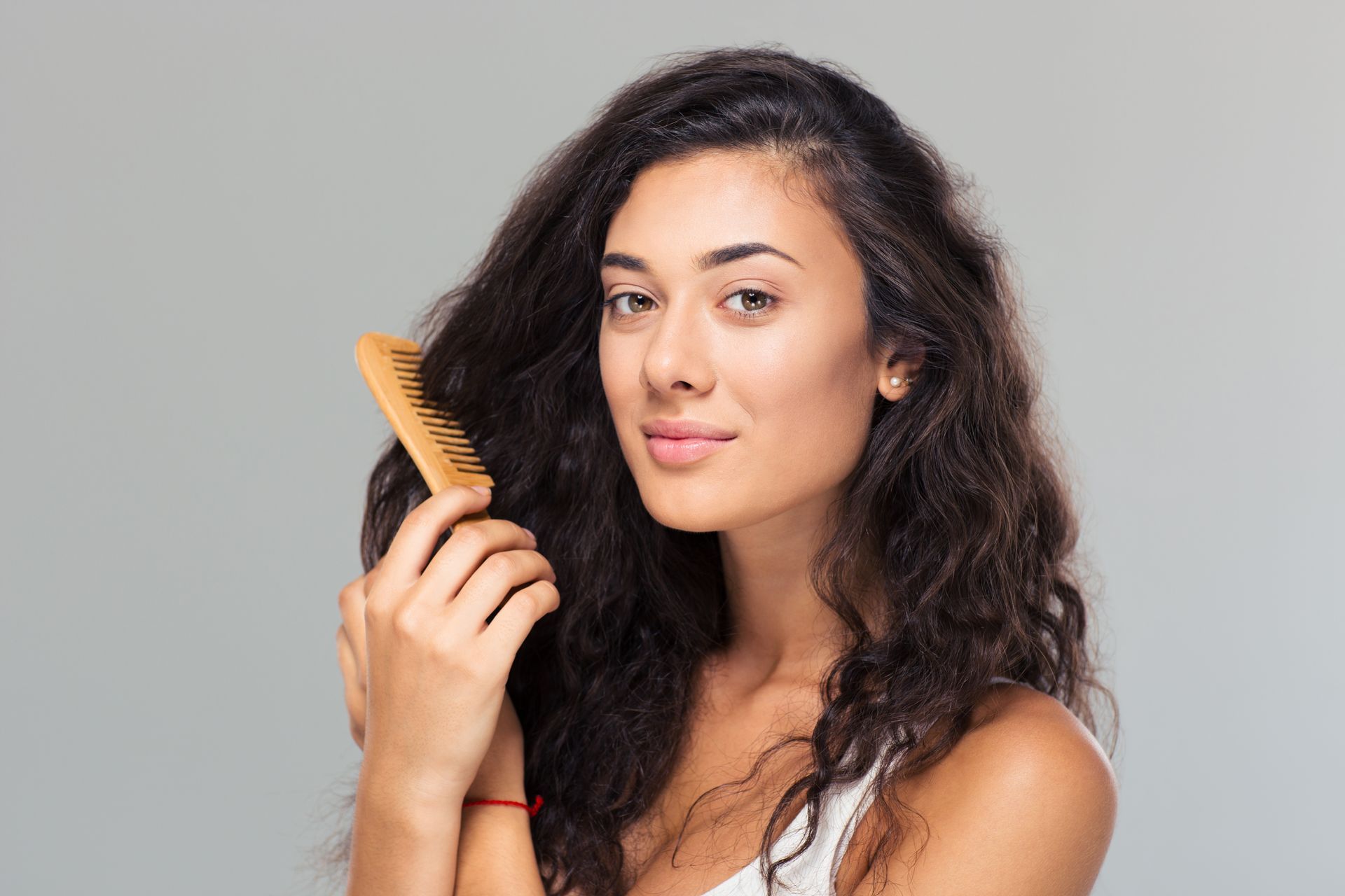 A woman is brushing her hair with a wooden brush.