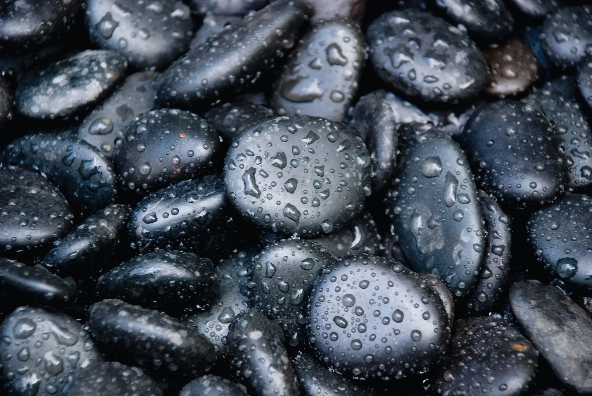 A pile of black rocks with water drops on them