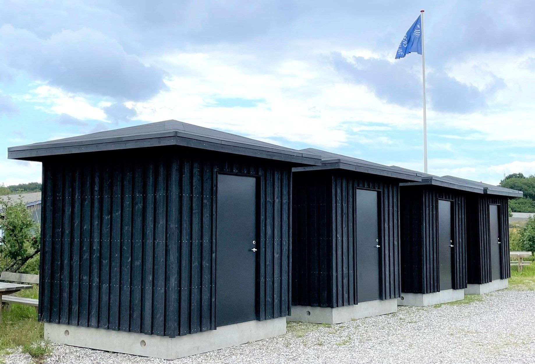 En række sorte skure med et blåt flag i baggrunden