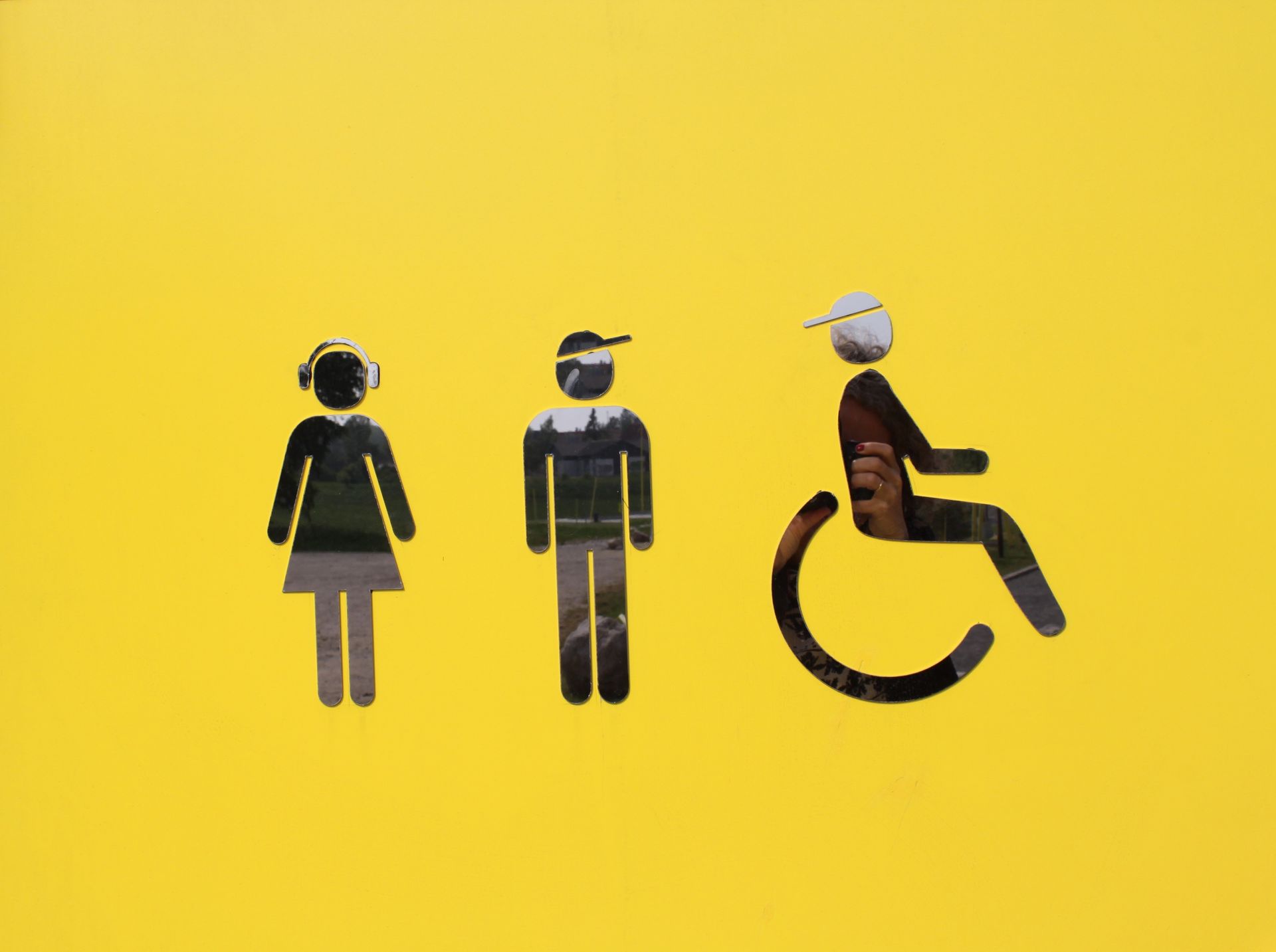 En mand i kørestol sidder ved siden af ​​en kvinde og en mand med høretelefoner.