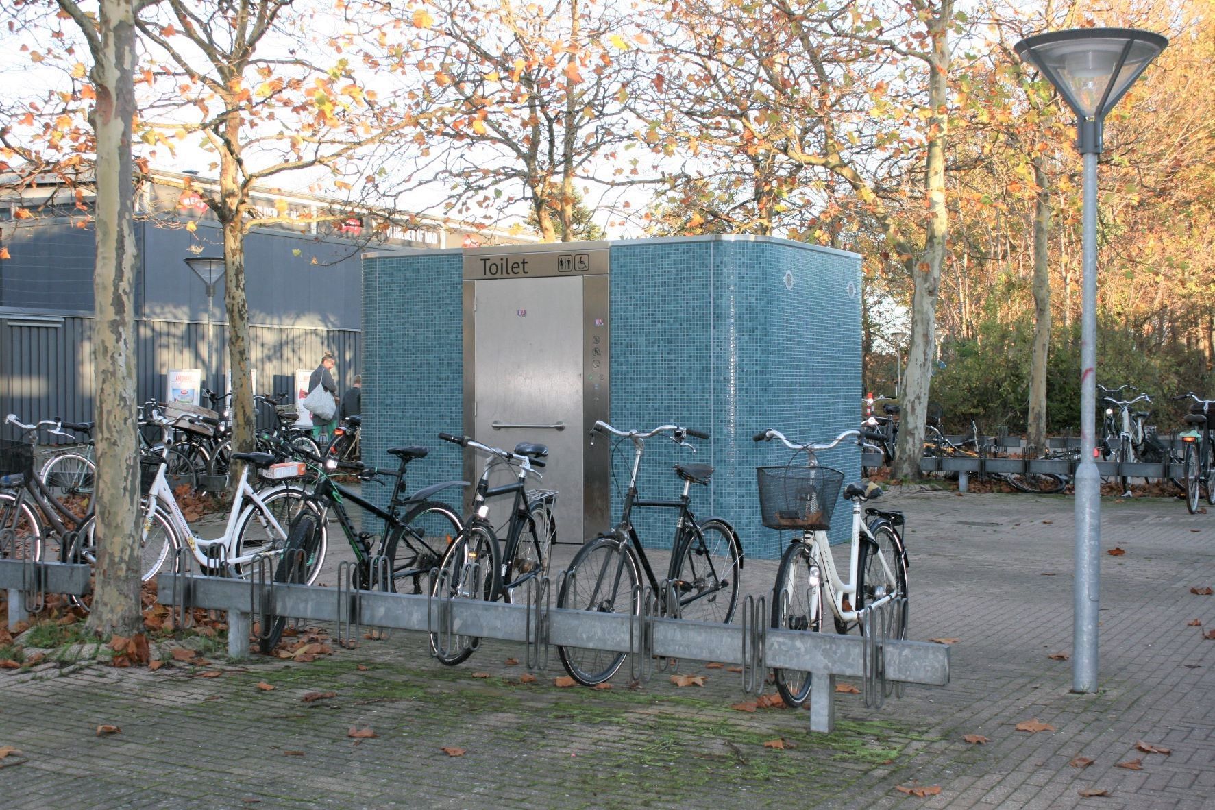 En række cykler er parkeret foran en blå bygning