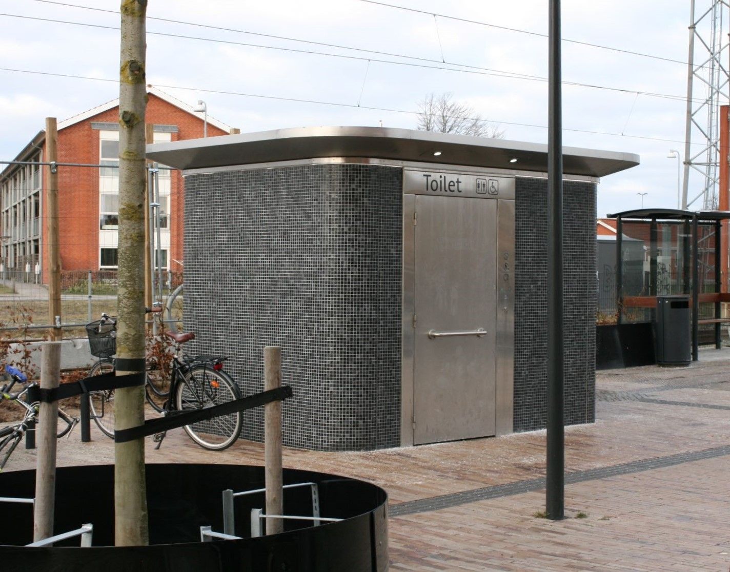 en lille træbygning med en hvid dør ligger på hjørnet af en vej