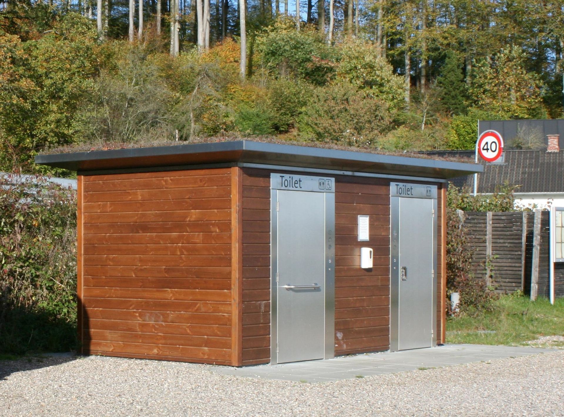 En træbygning med døre i rustfrit stål og et hastighedsskilt