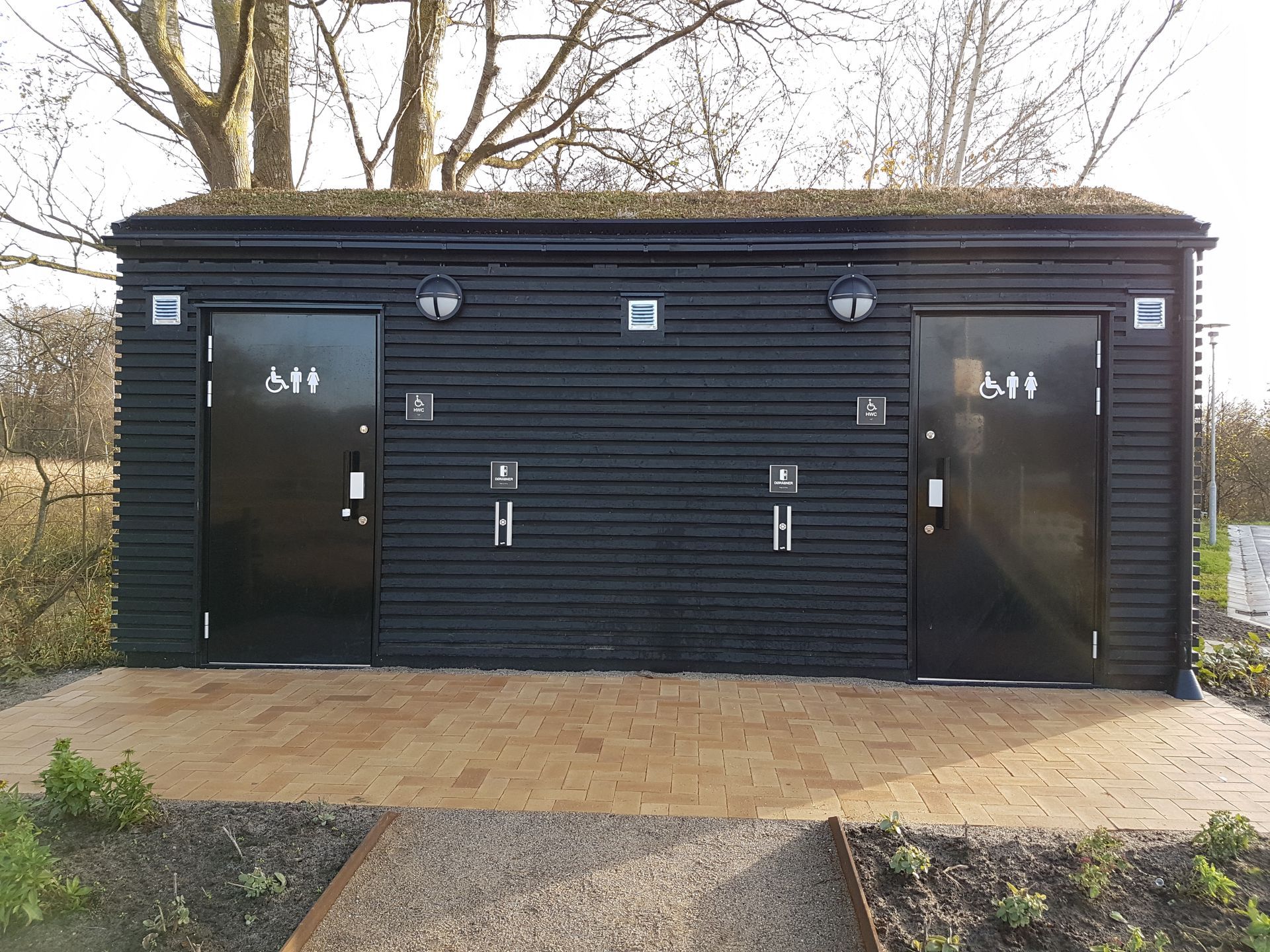 En sort bygning med to toiletter på siden af den.