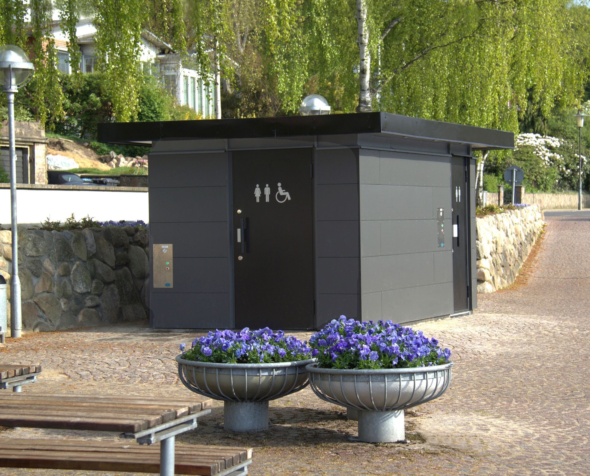 Et offentligt toilet med lilla blomster foran