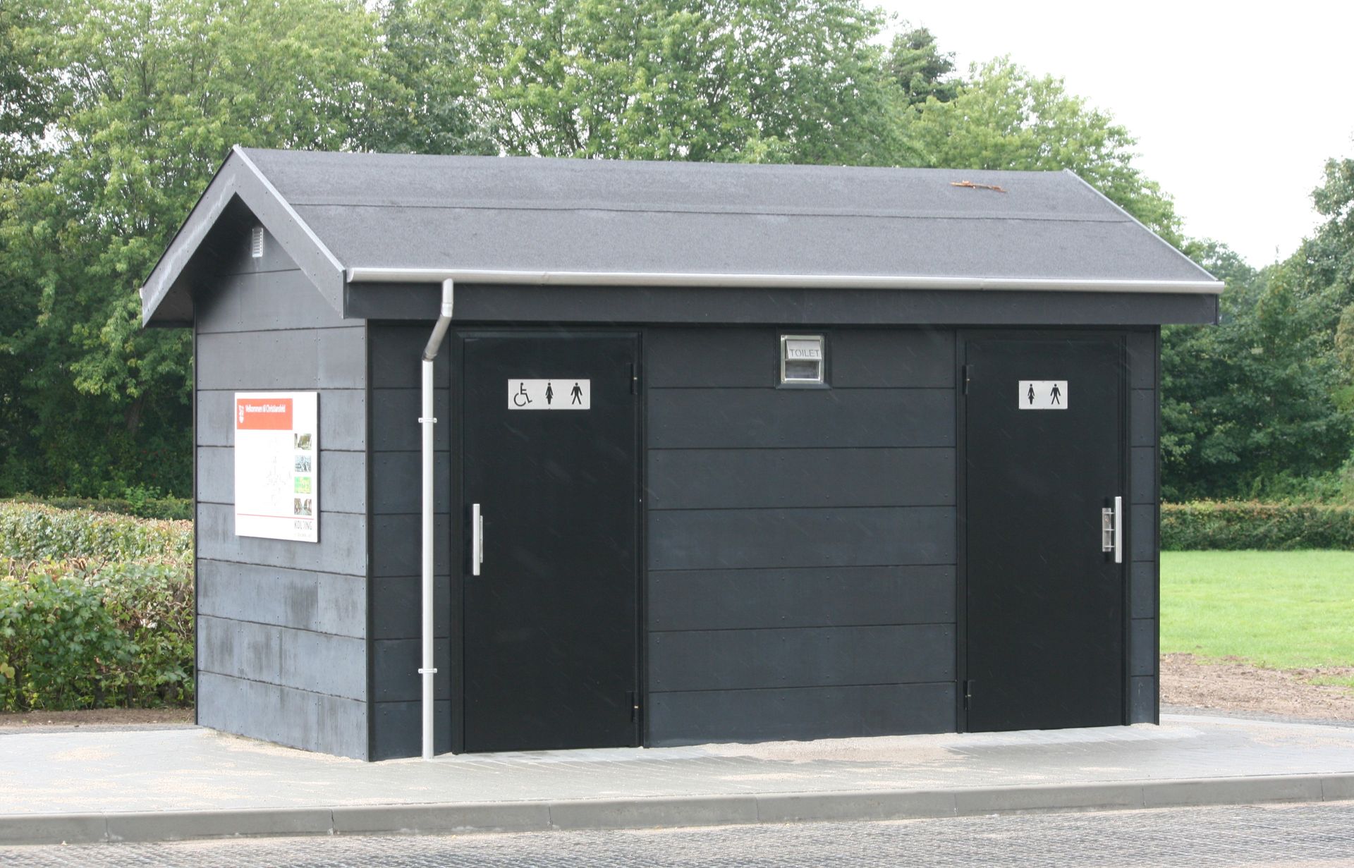 En lille sort bygning med to toiletter på