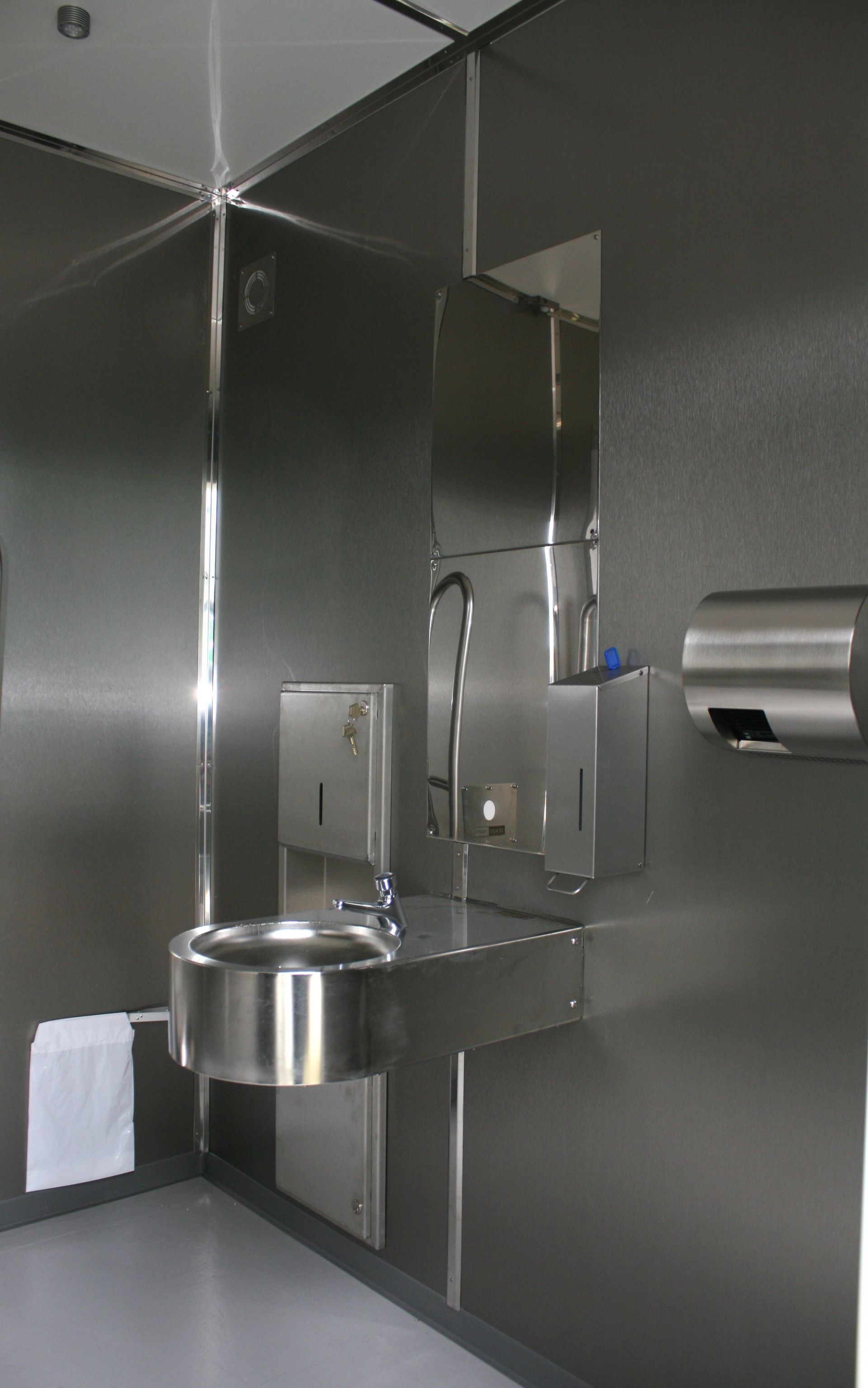 Et badeværelse med rustfri stålvægge og en vask