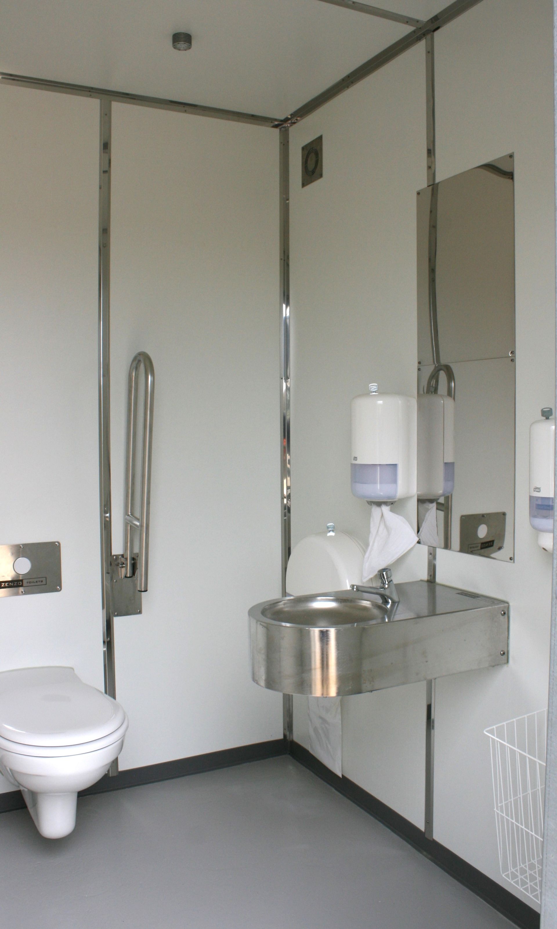 Et badeværelse med toilet, håndvask og spejl