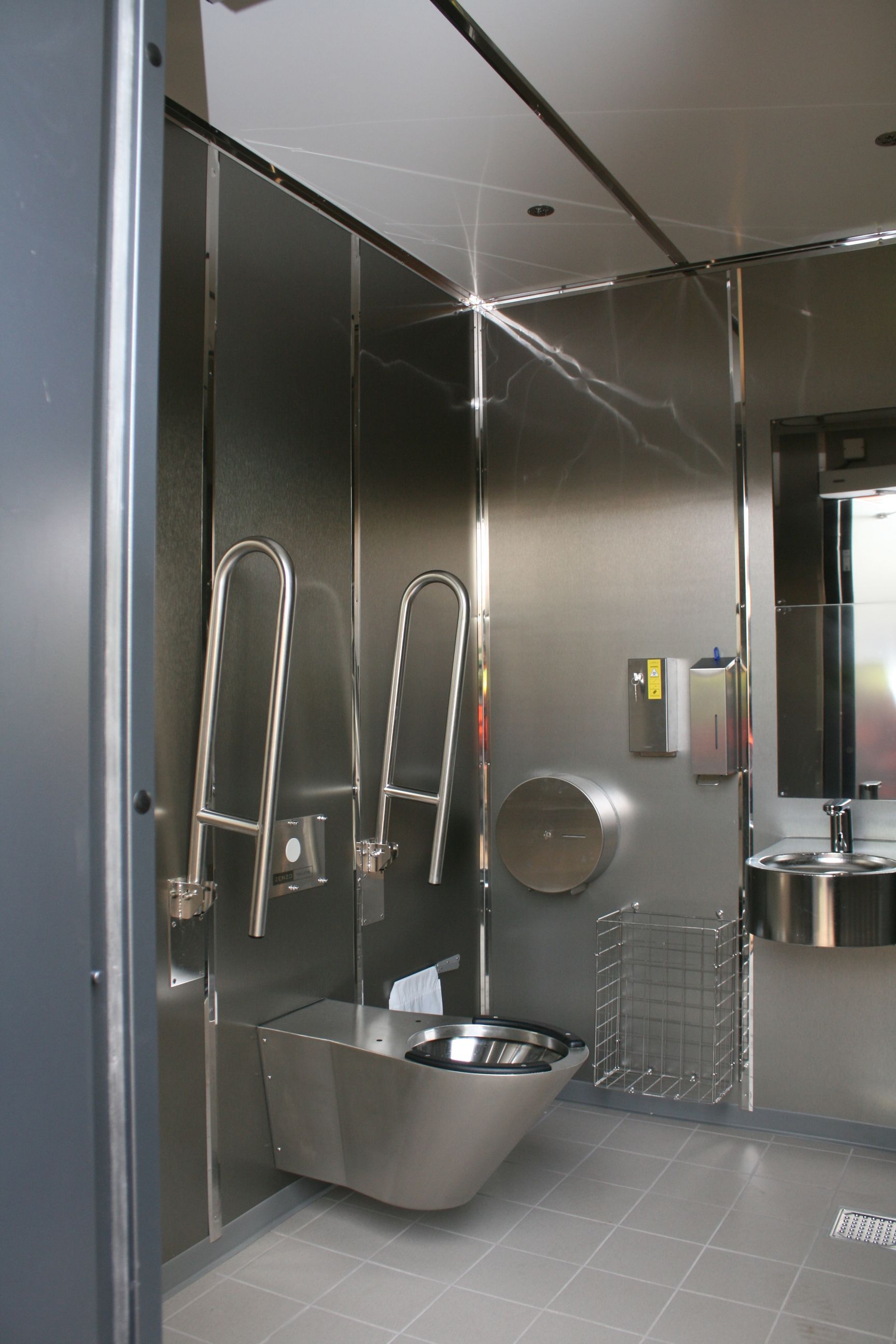 Et badeværelse i rustfrit stål med toilet og håndvask