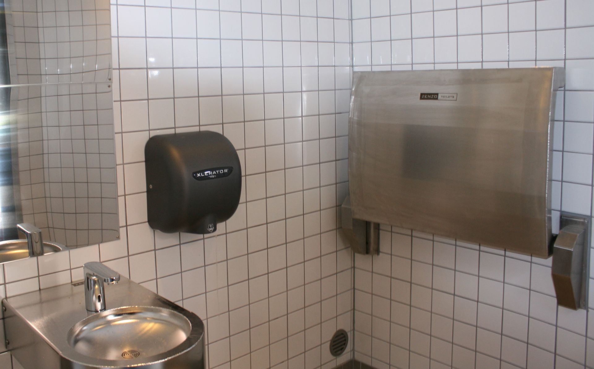 Et badeværelse med håndvask og håndtørrer