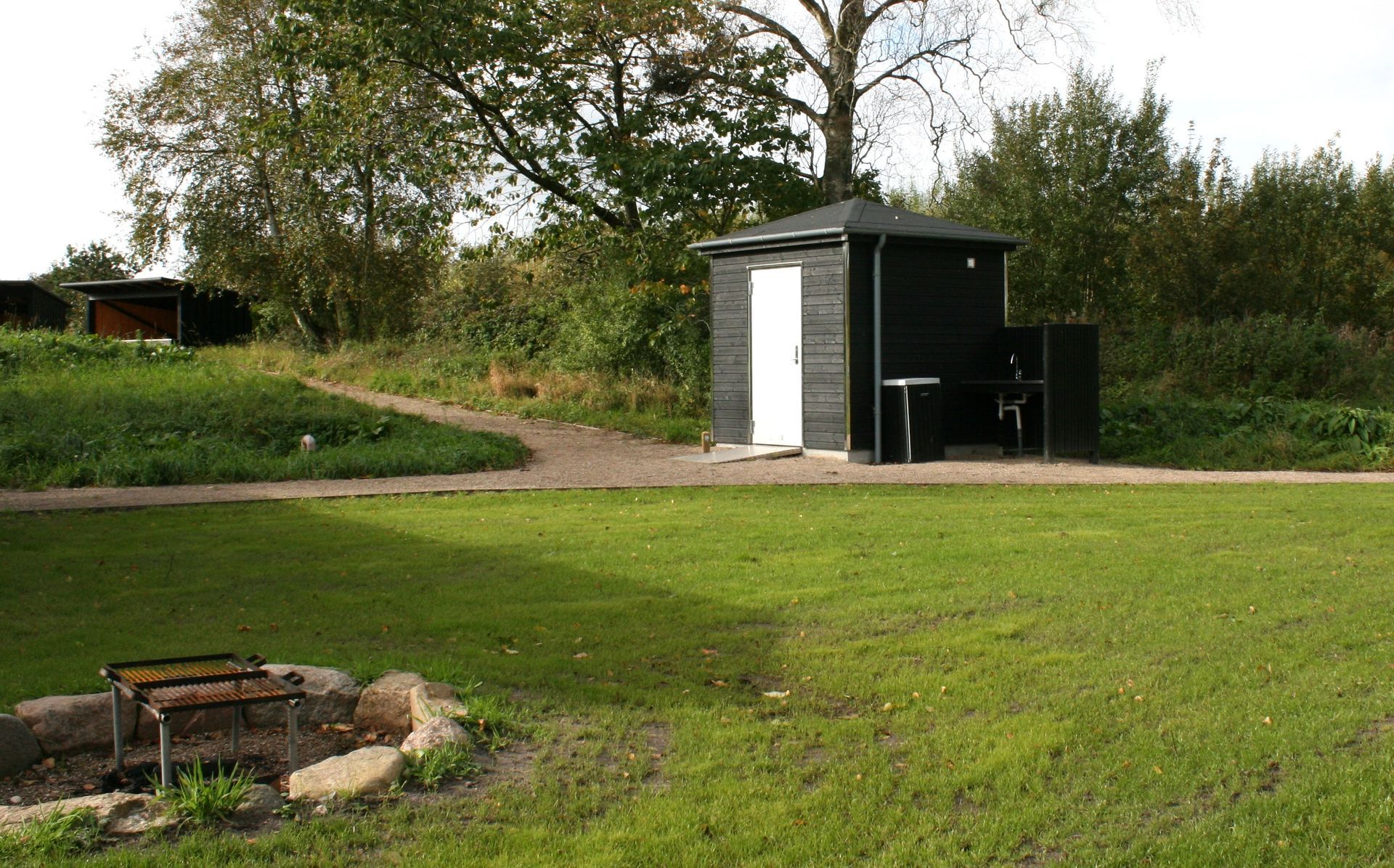 Et lille skur står midt på en frodig grøn mark.