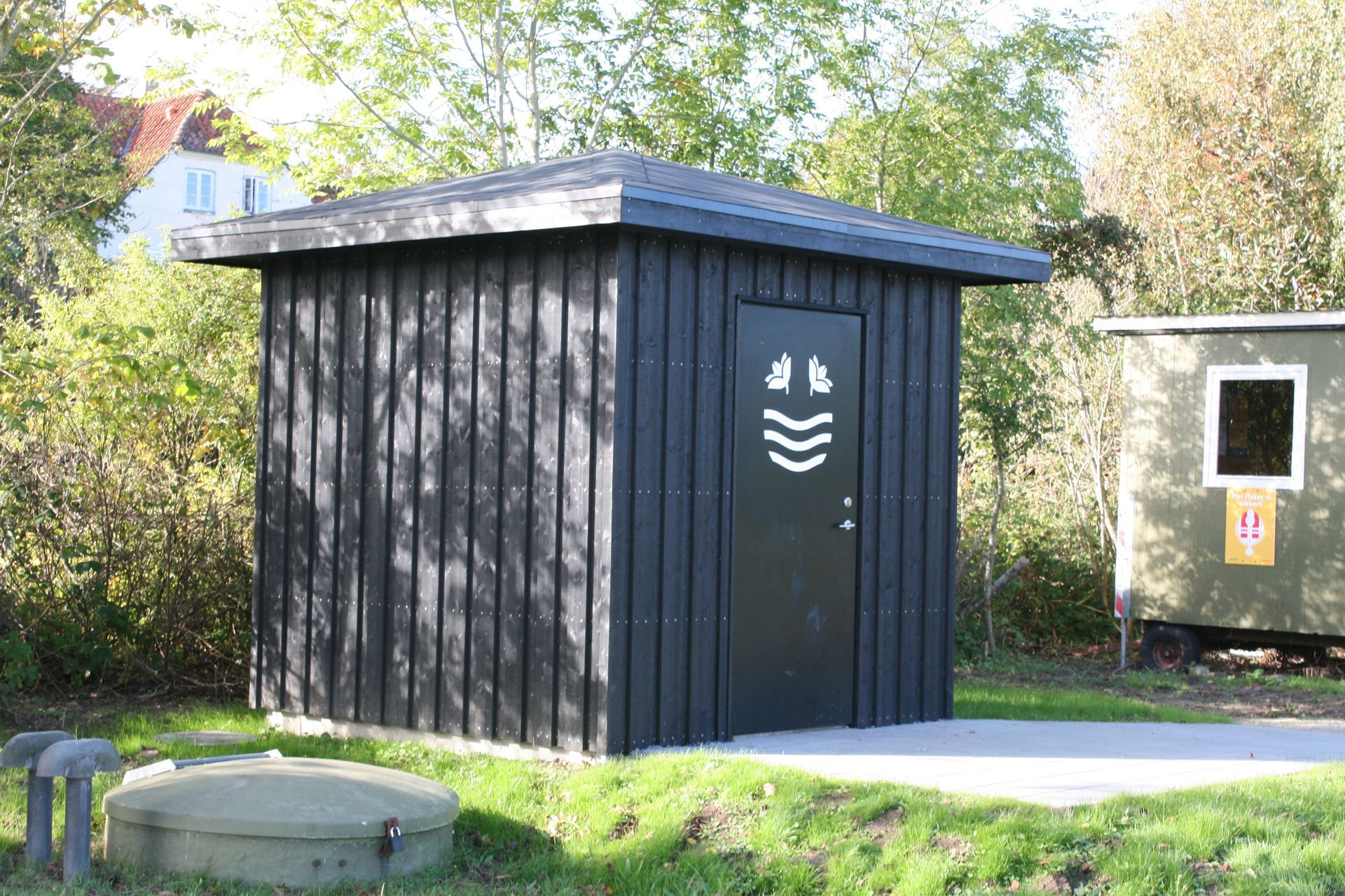 Et lille sort skur sidder midt på en græsmark.