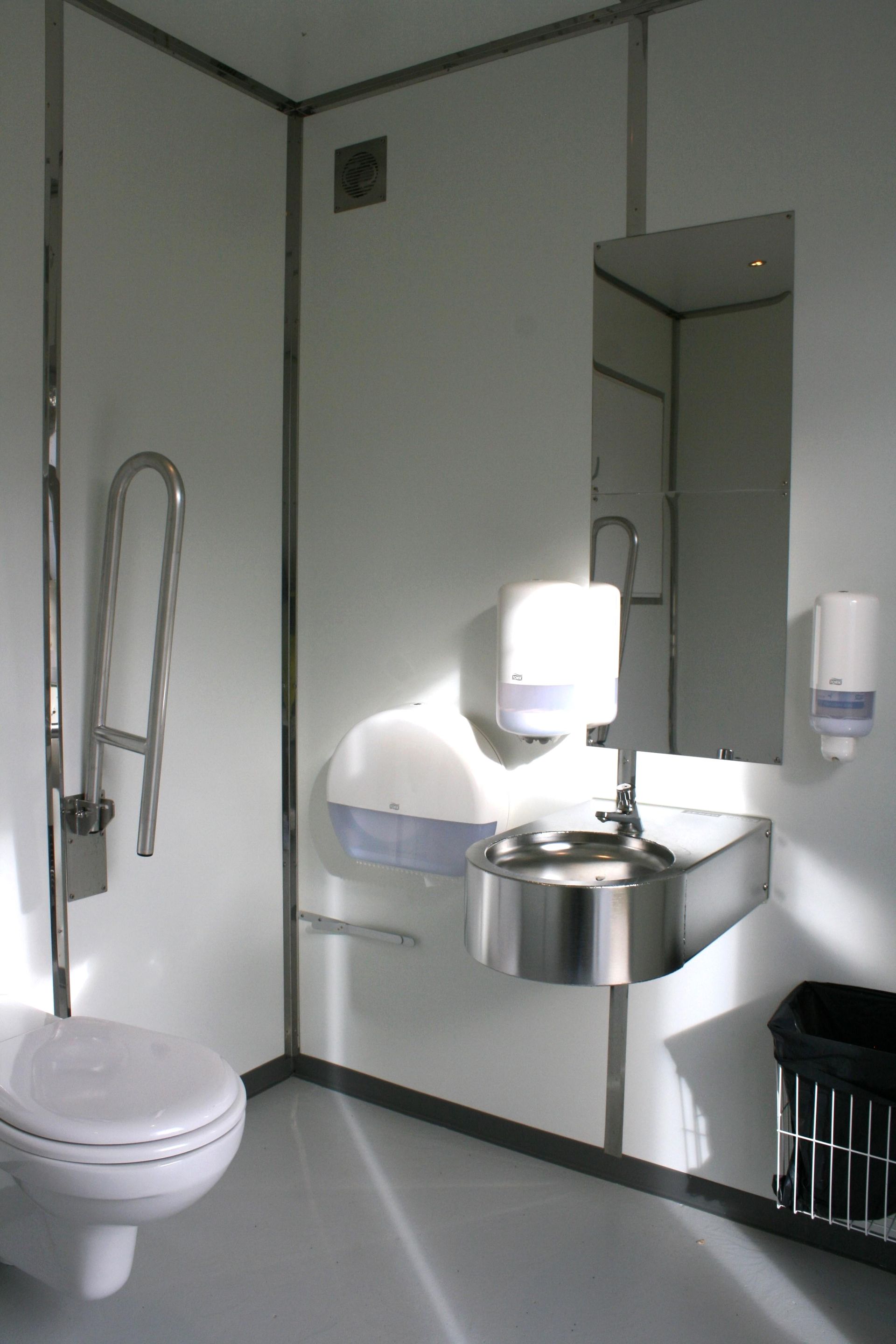 Et badeværelse med toilet, håndvask og spejl