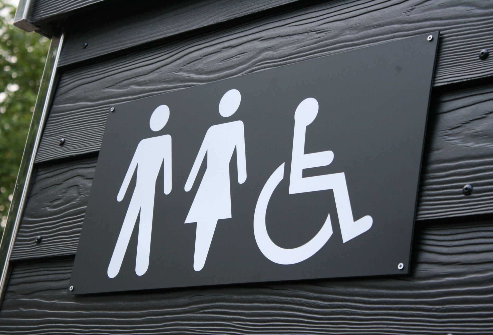 Et sort skilt med to personer og en kørestol på