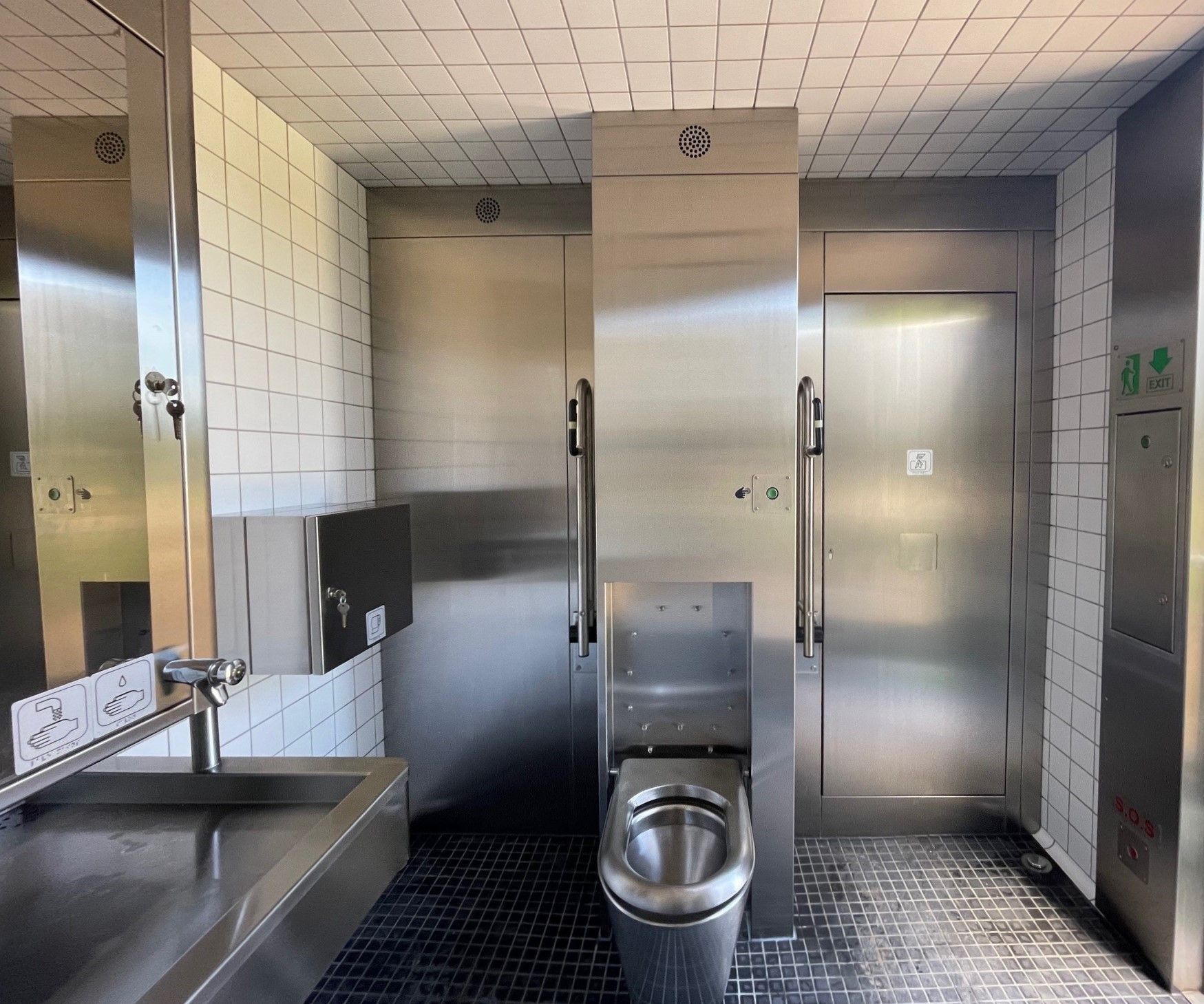 Et badeværelse i rustfrit stål med toilet og håndvask