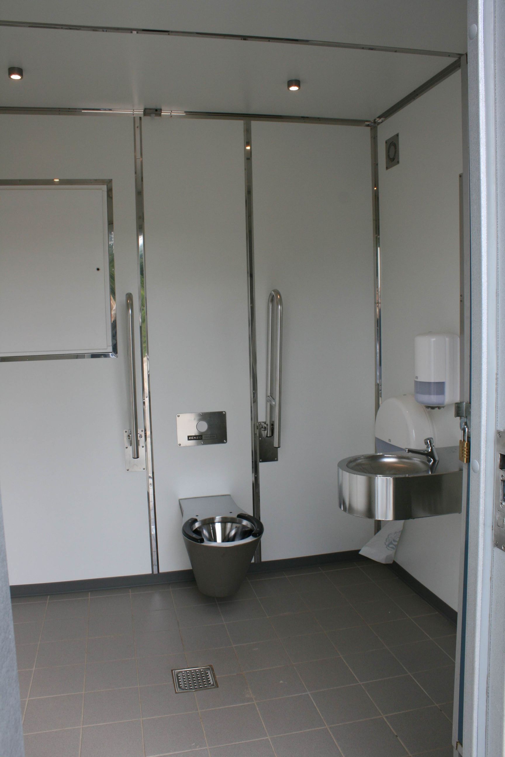 Et badeværelse med et rustfrit stål toilet og håndvask