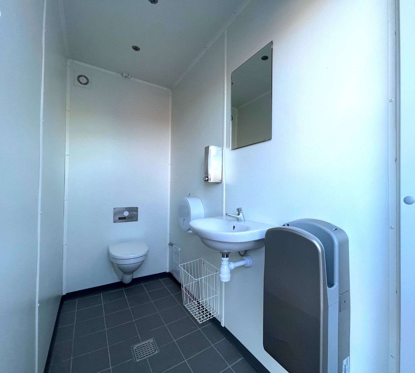 Et badeværelse med toilet, håndvask og spejl