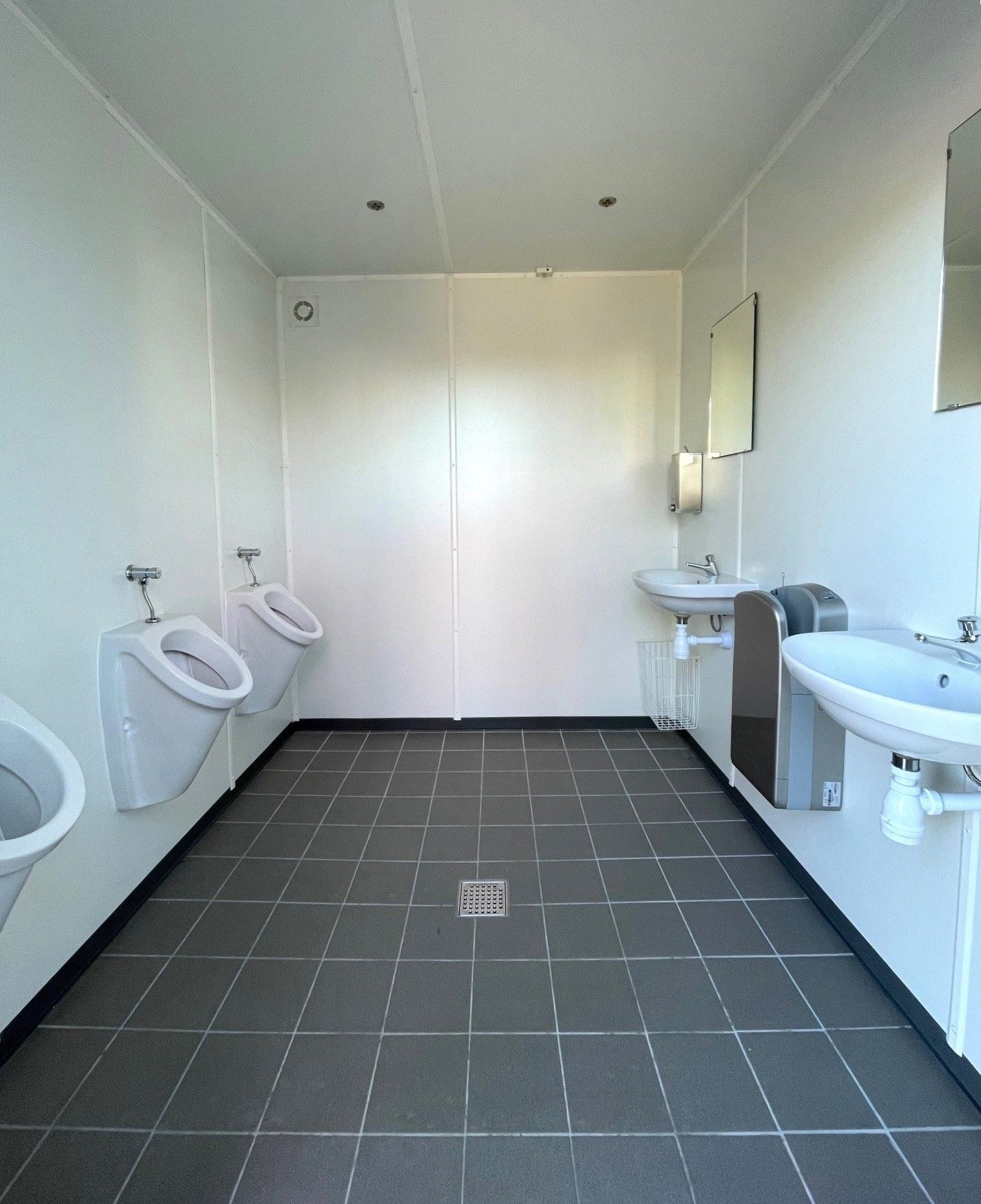 Et badeværelse med urinaler og håndvaske i det